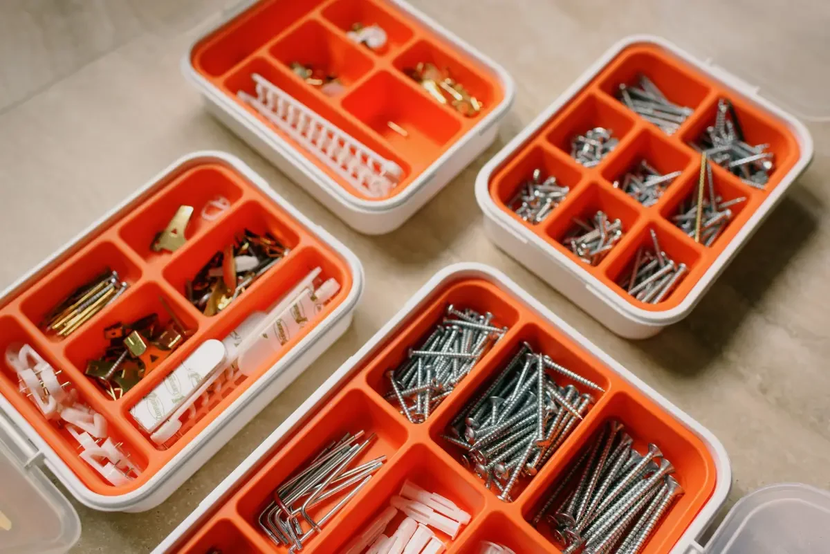 Vis et fixations assorties soigneusement disposées dans des boîtes en plastique pour des projets DIY.